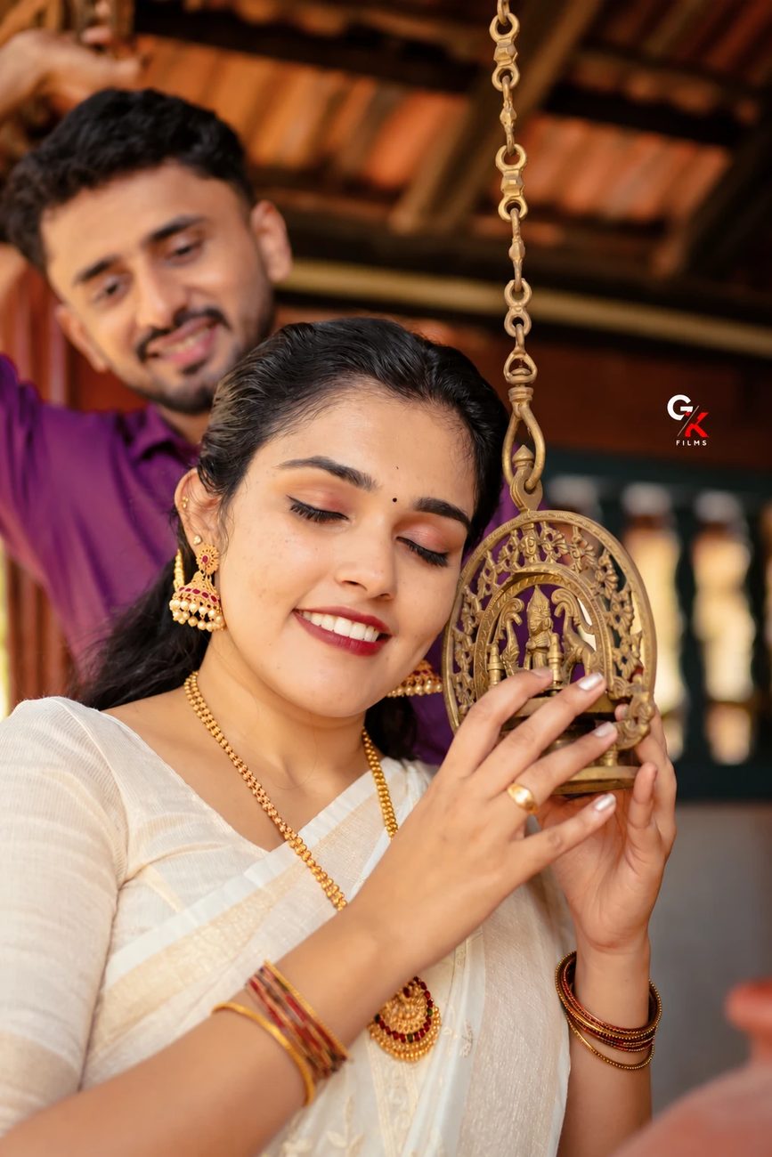 Manisha holding a brass hanging lamp, Pawan smiling behind her