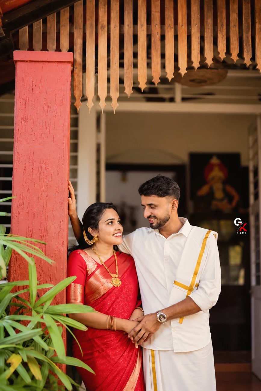 Manisha and Pawan looking at each other by a red pillar in front of the door