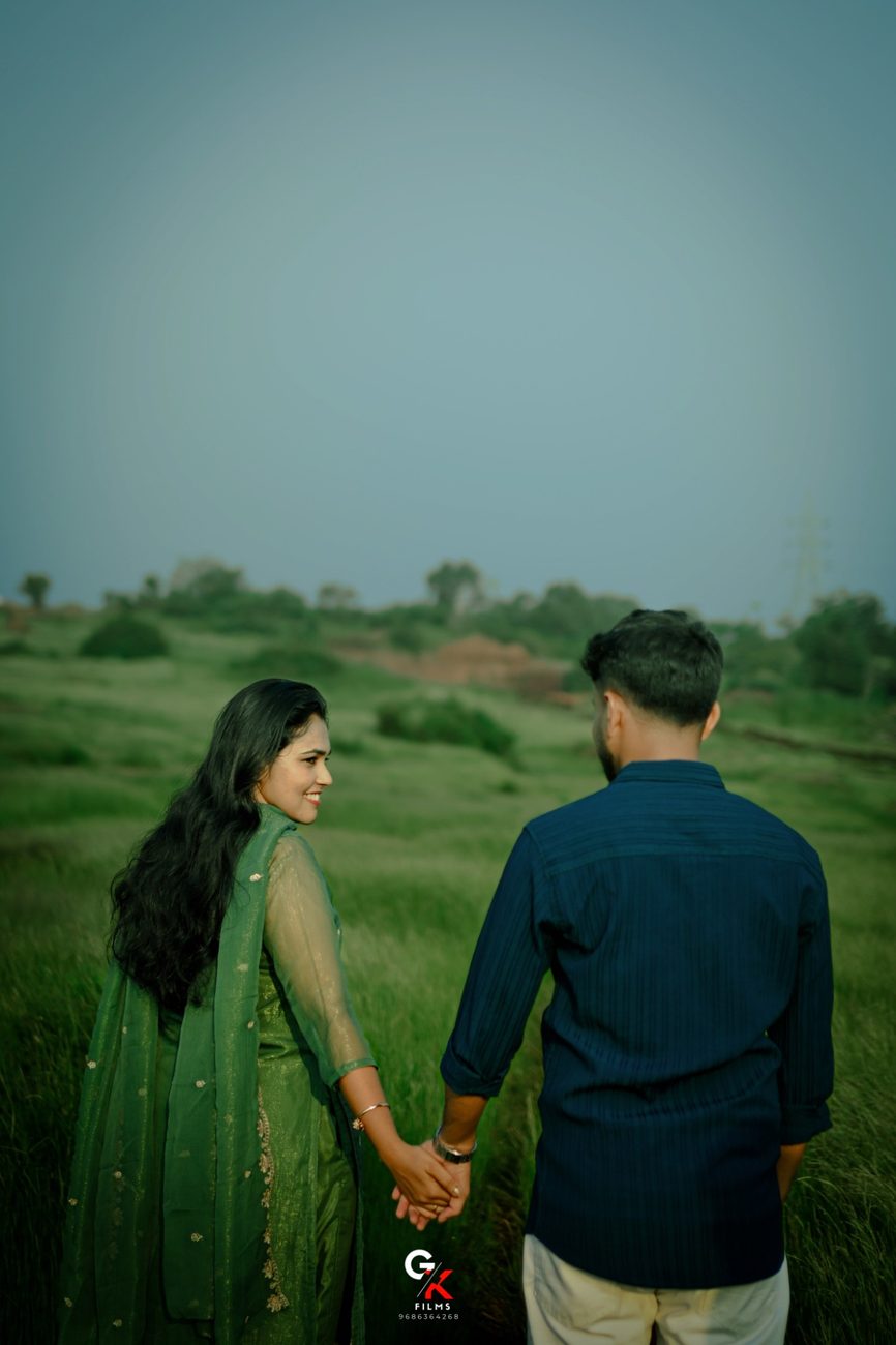 Manisha and Pawan walking hand in hand through a grassy field, Manisha looking back
